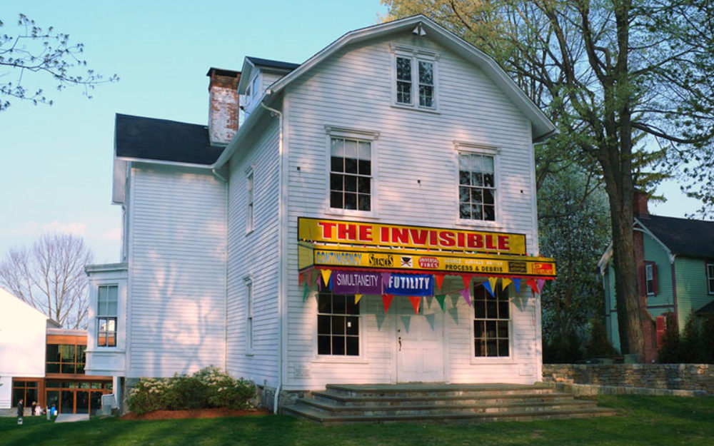 Image of The Aldrich's Old Hundred admin building with a yellow and red banner reading, "The Invisible"