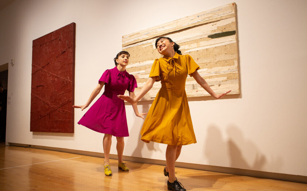 Two dancers in colorful dresses dancing in the gallery