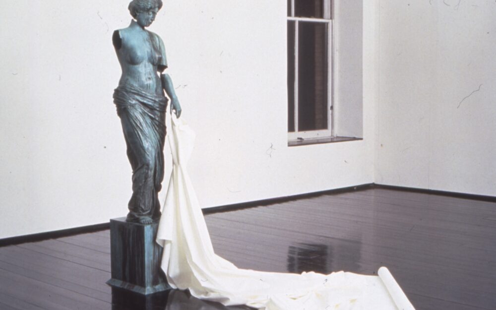 Bronze statue of a nude woman with white cloth draped in a train