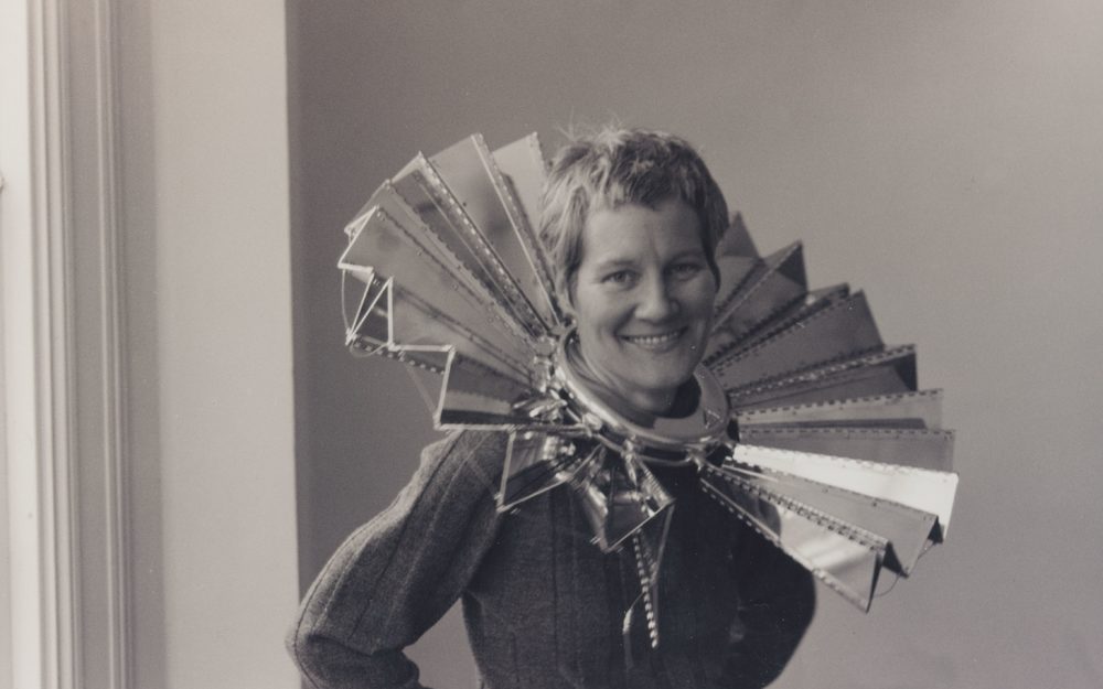 This is a photo of the artist Ann Hamilton with one of her metallic sculptures around her neck. She received the Larry Aldrich Foundation Award in 1998