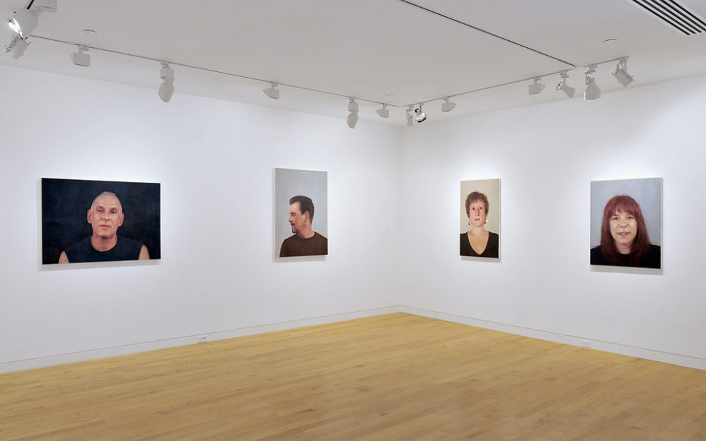 Four portraits hang on the gallery walls