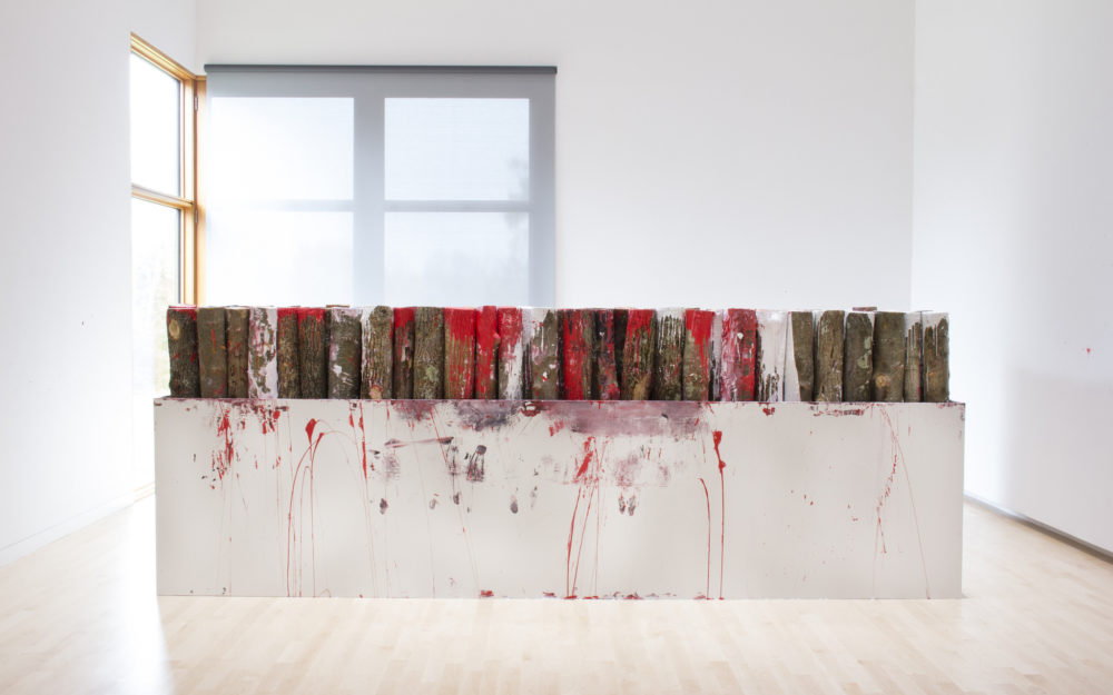 Wood covered in red paint placed in a white sculpture
