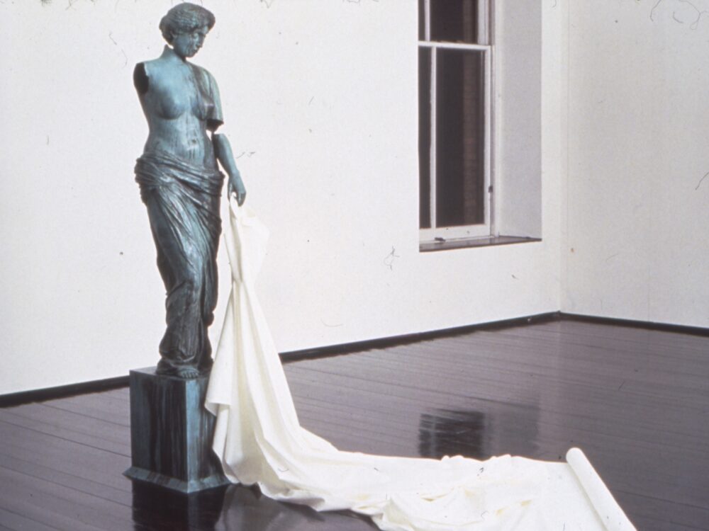 Bronze statue of a nude woman with white cloth draped in a train