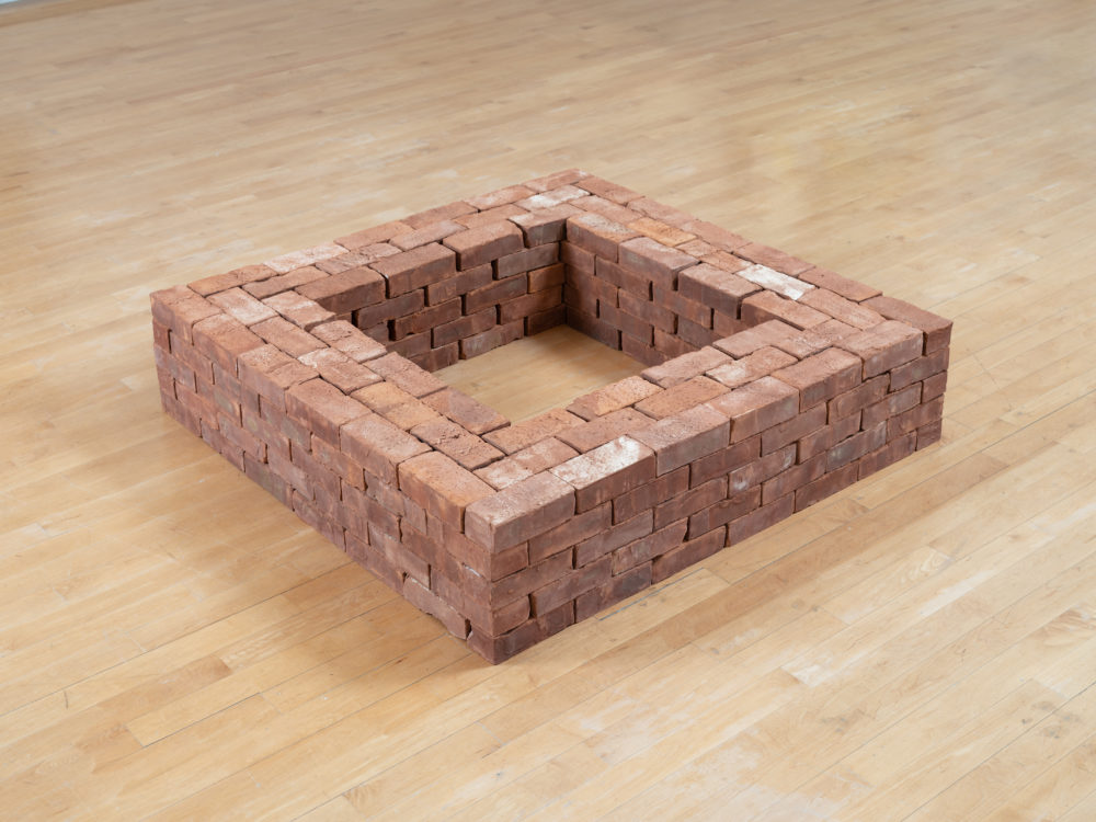 Square sculpture made of stacked, loose bricks
