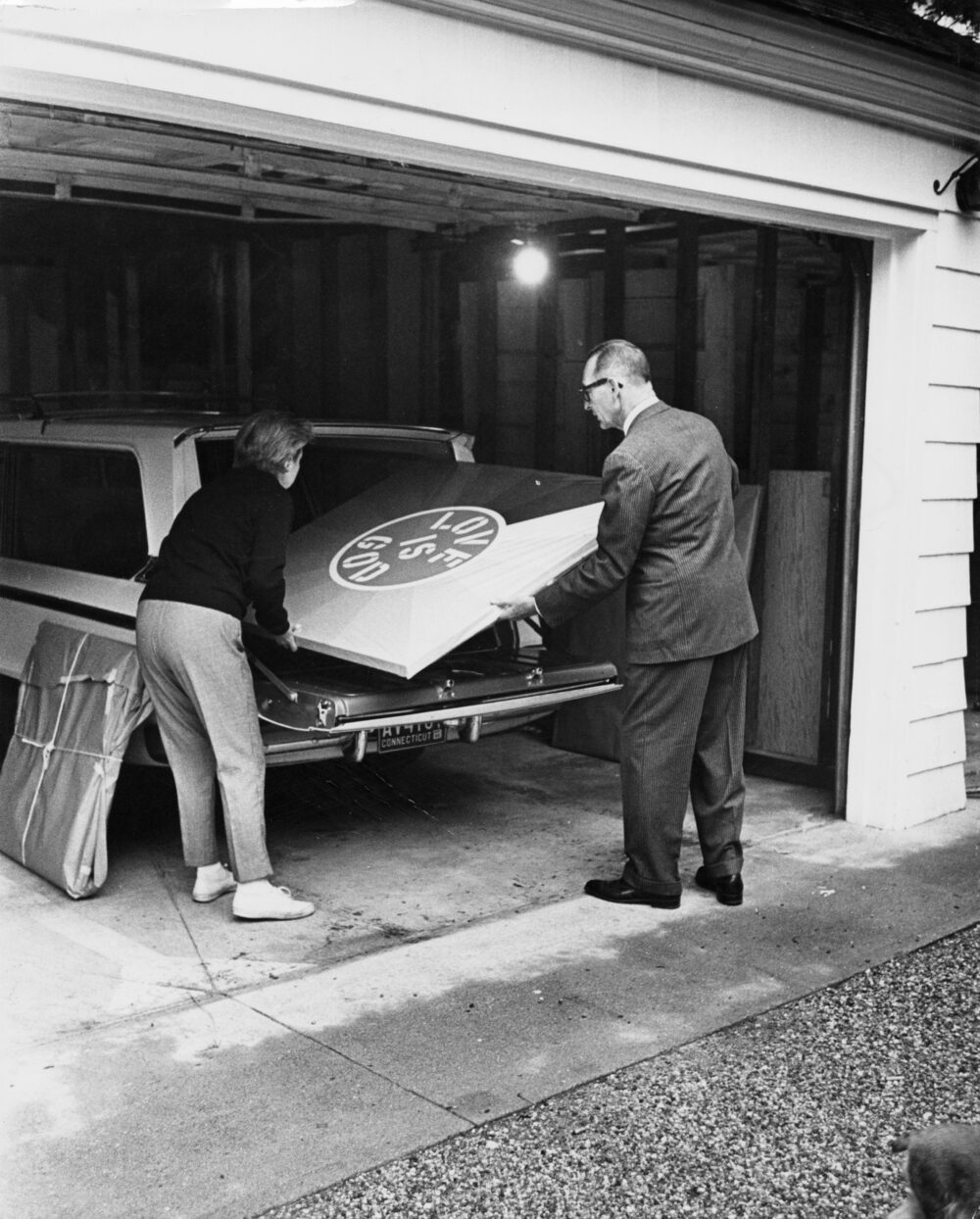 Larry Aldrich loading Love Is God by Robert Indiana into the back of a station wagon for transport.