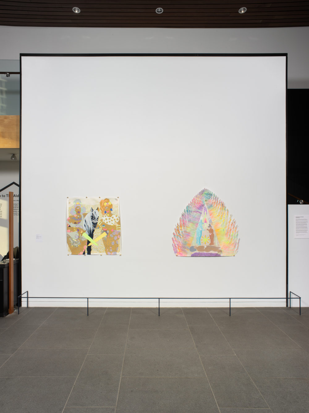 Two colorful figurative works with many symbols hung on a white wall.