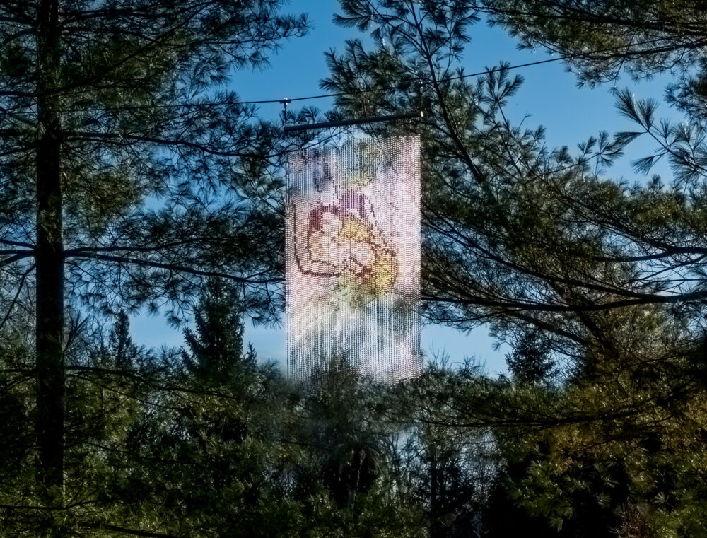 a curtain made of colorful glass and steel beads installed on a branch of a tree