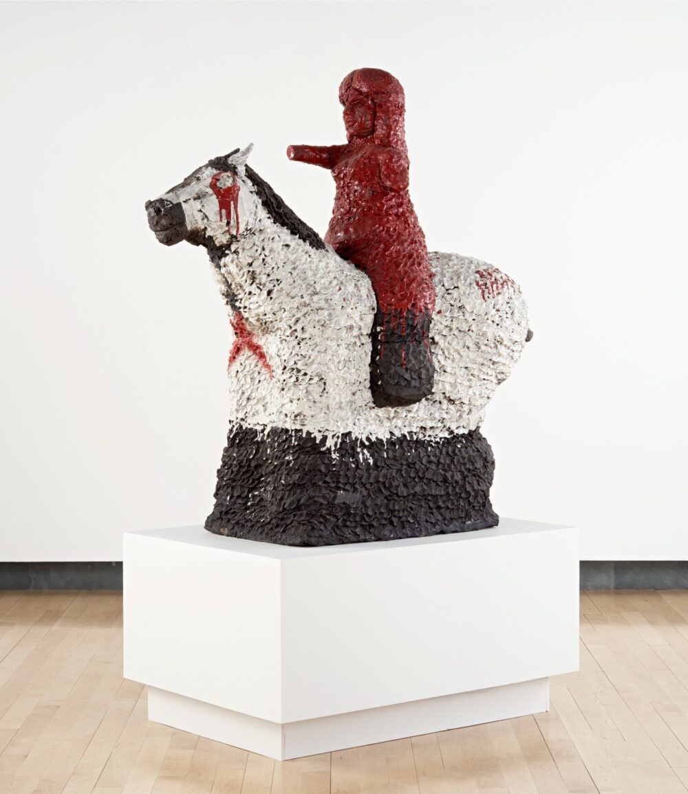Ceramic sculpture with a red rider on a white horse.