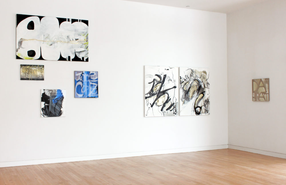 Salon style hung gallery wall with abstract paintings.