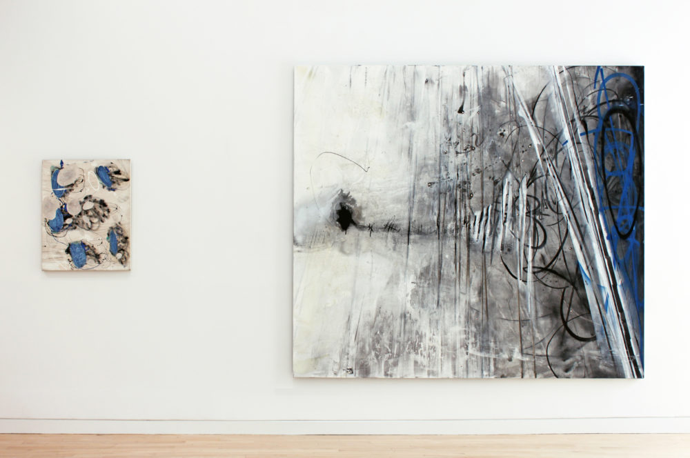 A small abstract painting to left and a large abstract painting to the right.