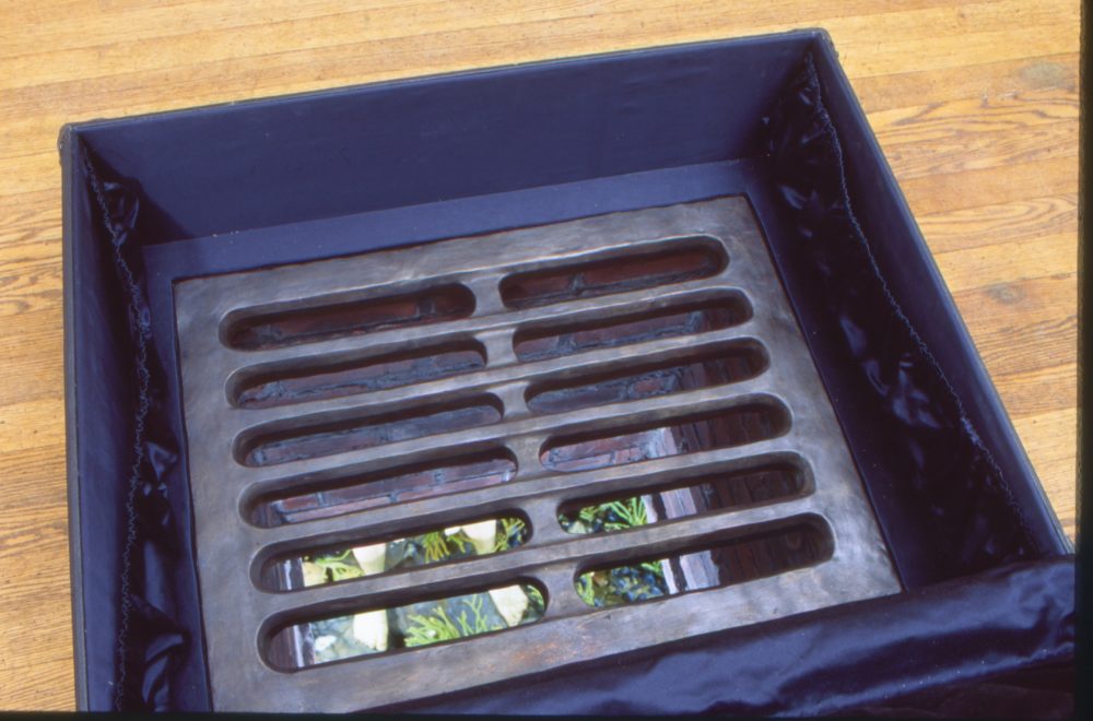 A drain inside a suitcase which has two appearing legs standing on a false ocean floor