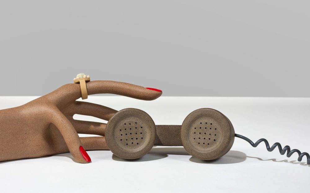 Ceramic hand reaches out towards a telephone