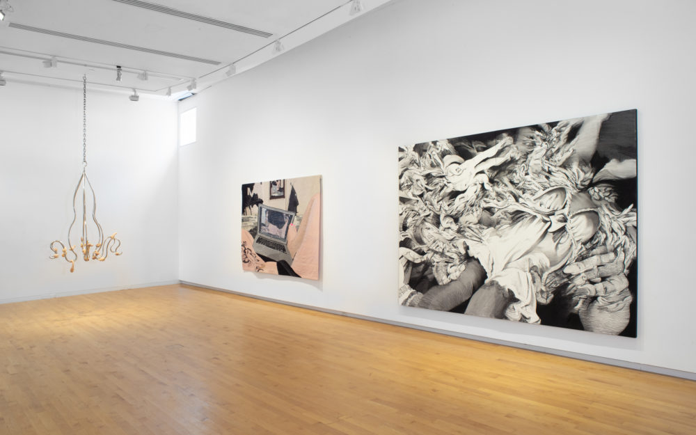 Gallery with a suspended sculpture on the far left, a tapestry at center and a large black and white work on paper at the right.