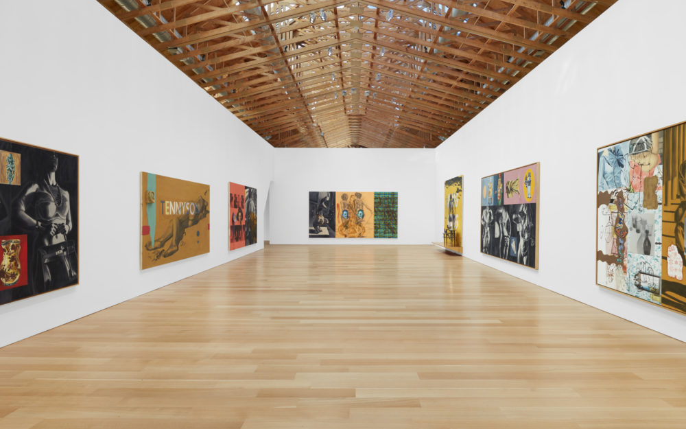 Gallery with wooden beamed on the ceiling and paintings on three walls.