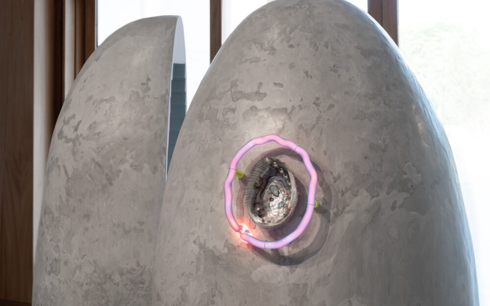 Detail of large sculpture focused in on a circular neon element around a shell.