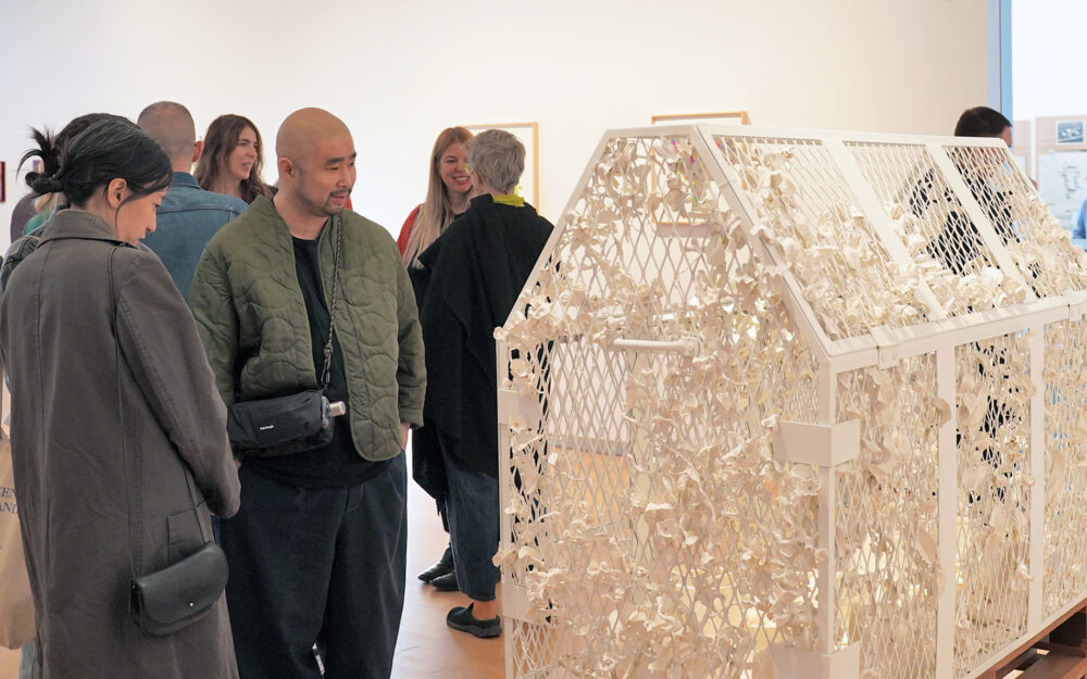 A group of people observing a sculptural art form in a museum space.