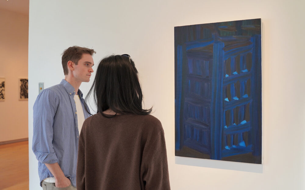 two visitors viewing a painting at an art museum