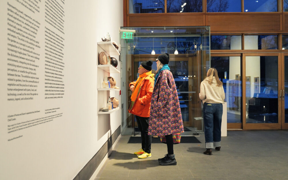 two people observing a wall installation in a museum space.