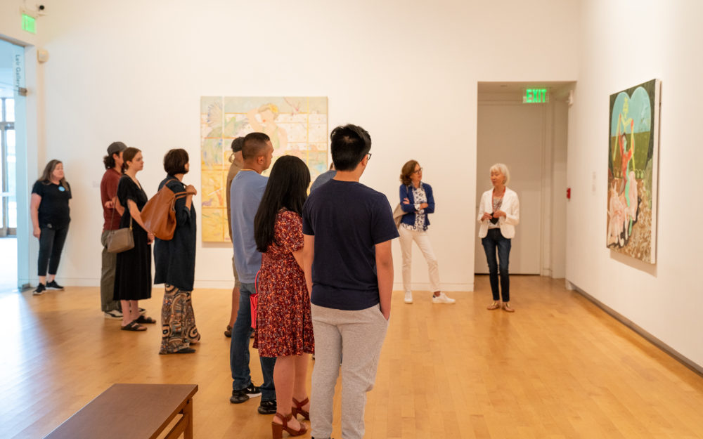 People in a gallery receiving a tour.
