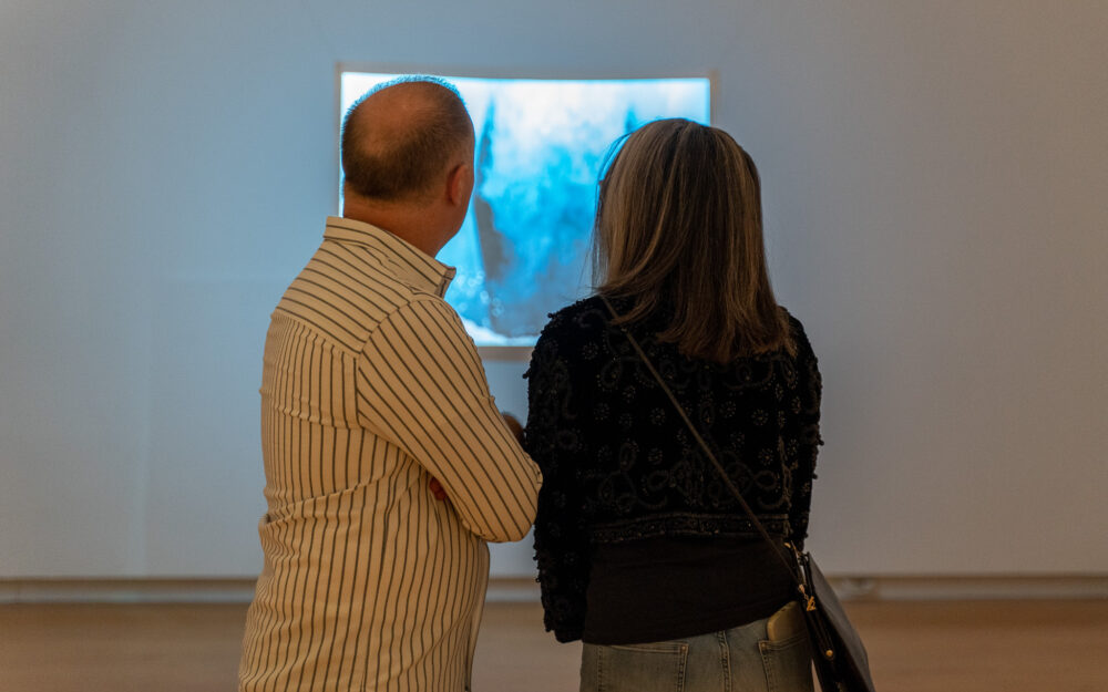 Two adults in an art museum looking at a projected video