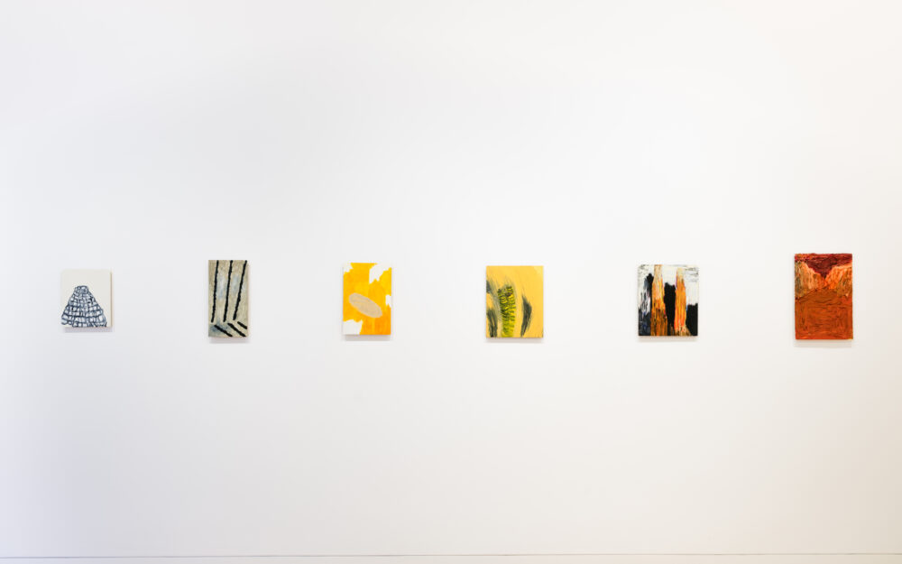 A white wall with a row of small abstract paintings