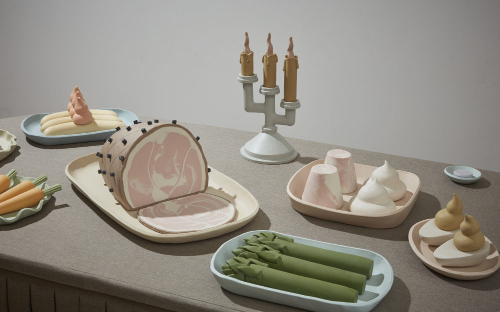Small sculptural food items arranged on a gray table