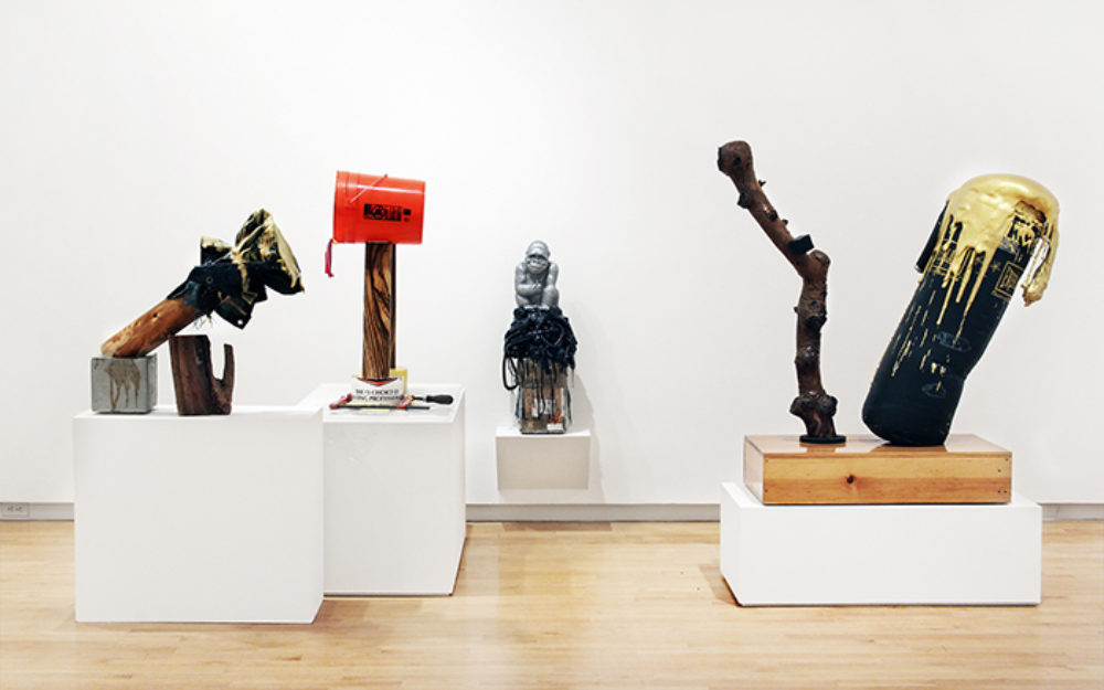 Four sculptural works sit on white platforms in gallery