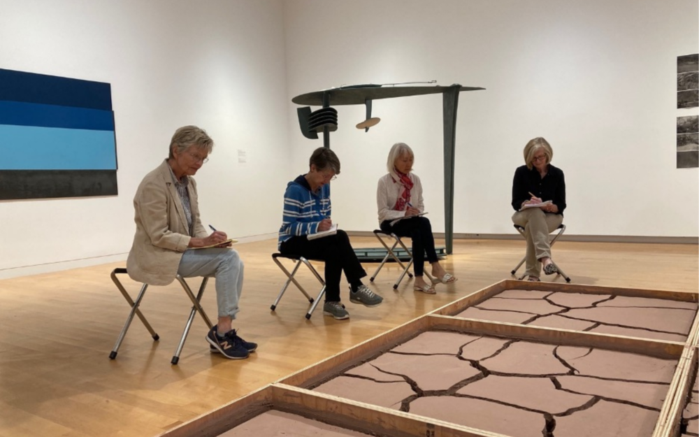 People sitting in an art gallery and writing