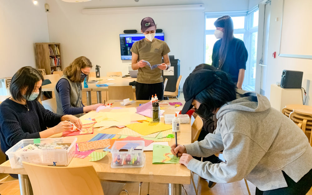 Teens around a table making zines with craft materials
