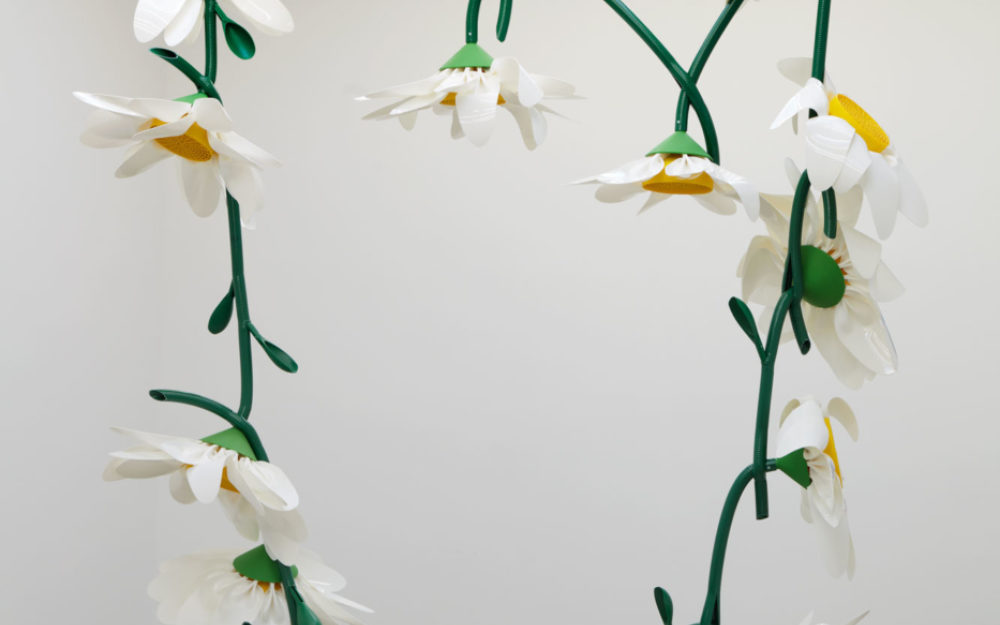 A large sculpture of a daisy chain with white flowers and green stems.