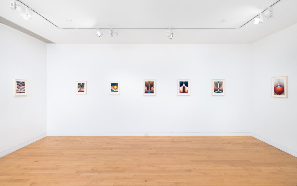 A row of small framed colorful drawings hung on three walls in a gallery