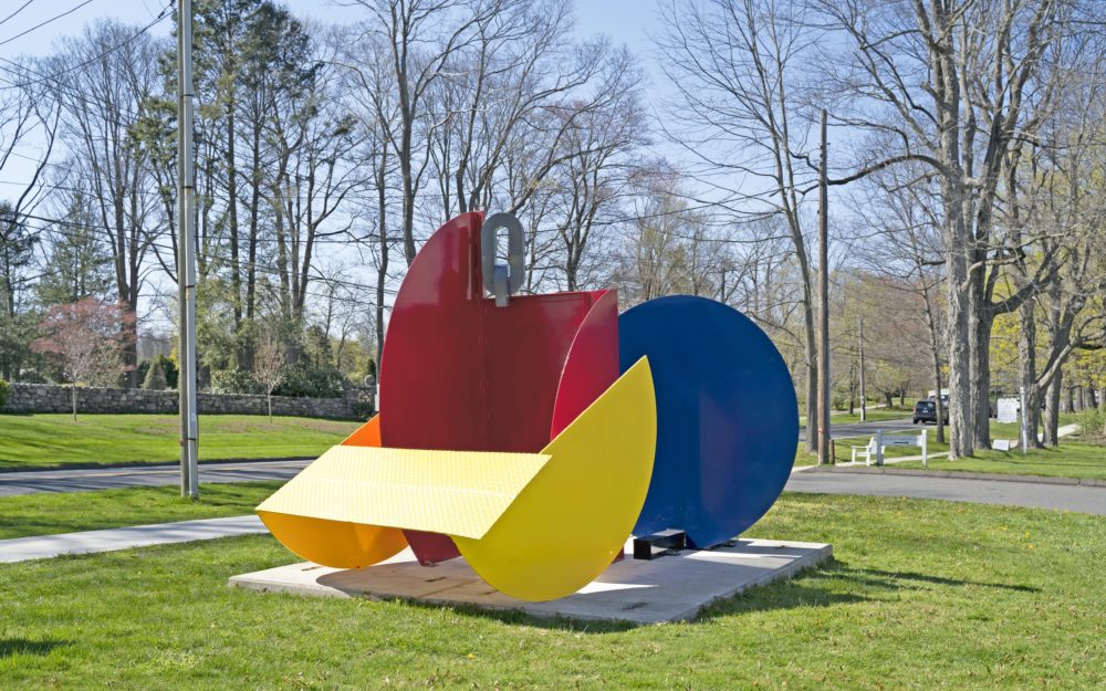 Abstract sculpture with primary color shapes on a lawn.