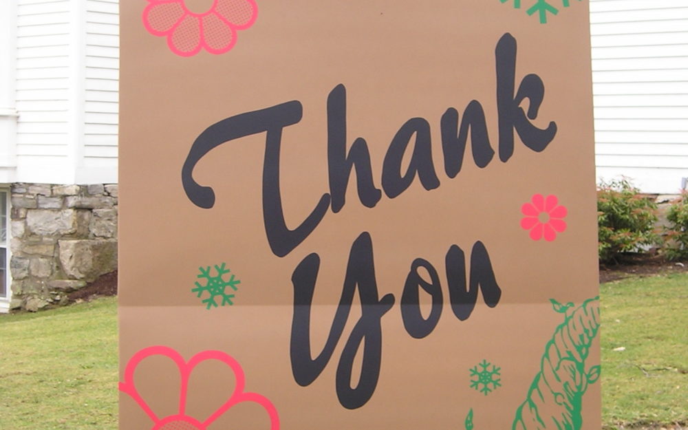 7-foot-tall "brown paper bag" sculpture installed on Museum lawn. "Thank You" in black with pink flowers, green cornucopia and snowflakes on front.