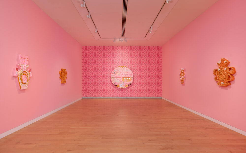 A pink room with pink hued paintings hung on the walls.
