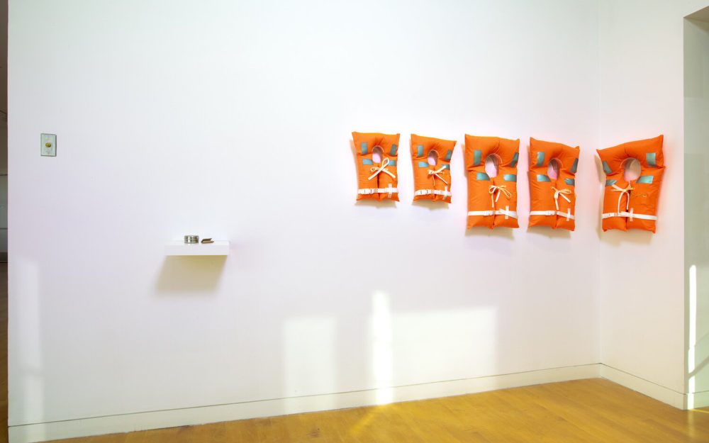 Five orange life jackets on gallery wall