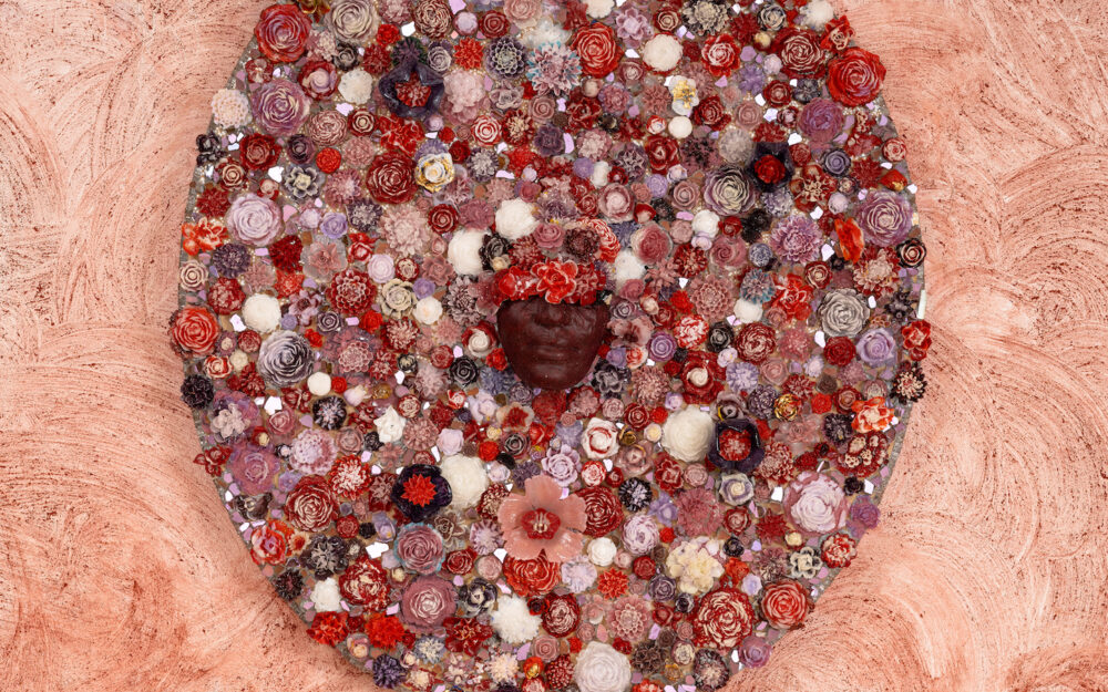 Glass collage with a face at the center surrounded by florals.