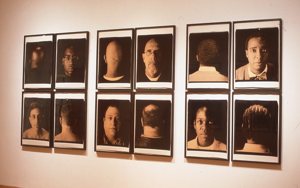 This is an installation image featuring six rows of portraits of subjects' faces and the back of their heads