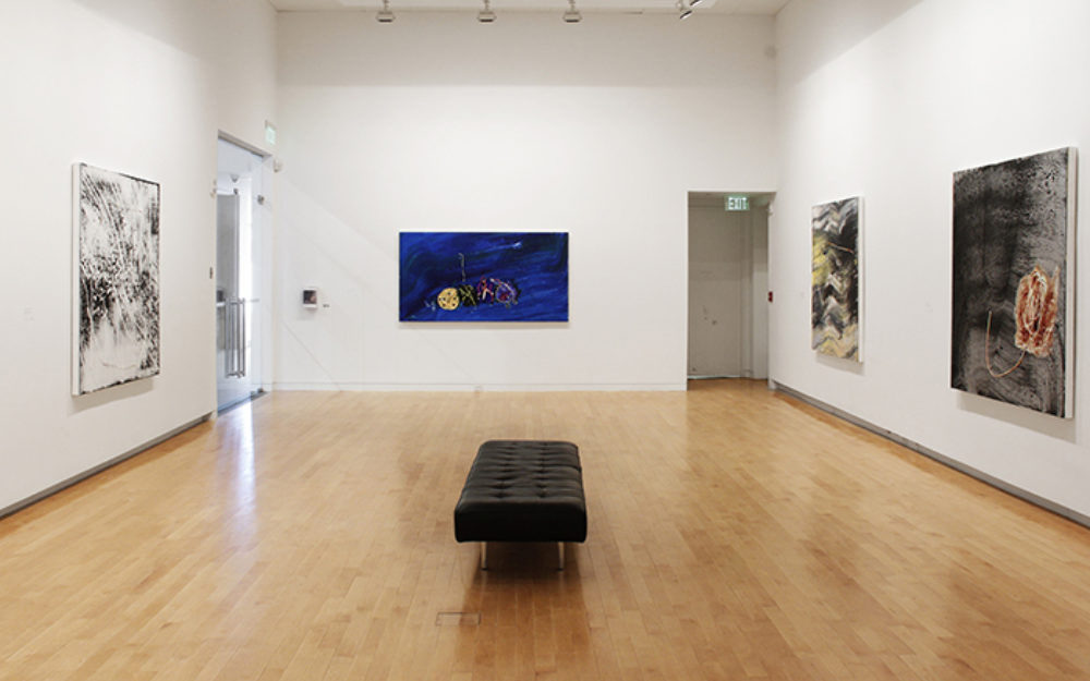 Jack Whitten's artwork hangs on the gallery walls, small black bench sits in the middle of the room