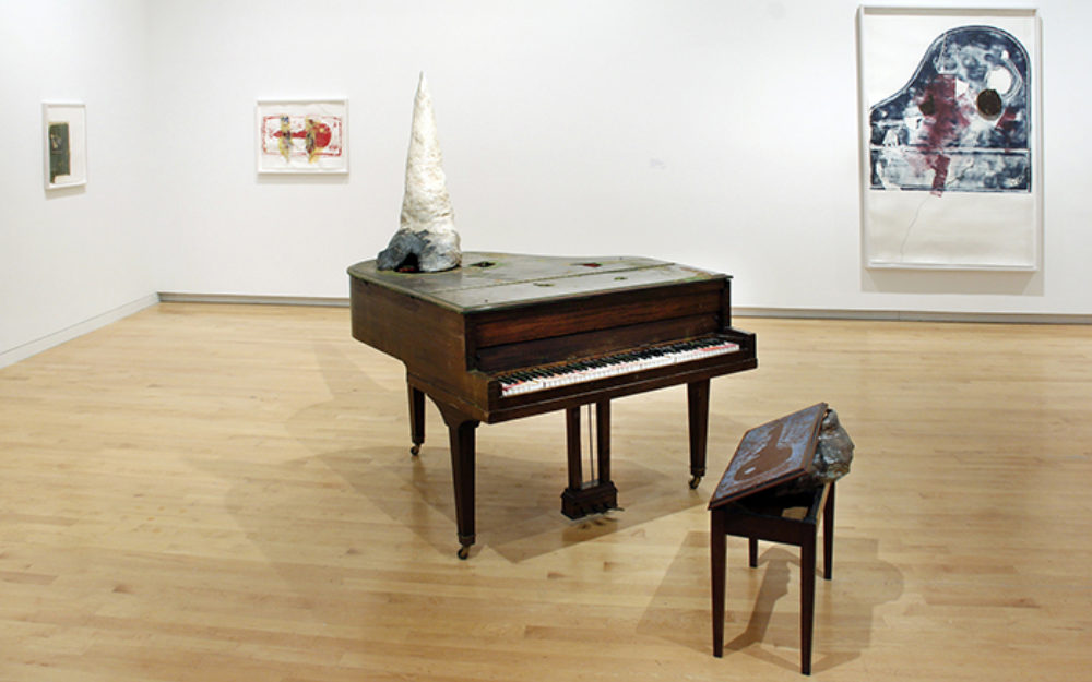 Piano sits in the center of room with a unicorn horn mounted on top