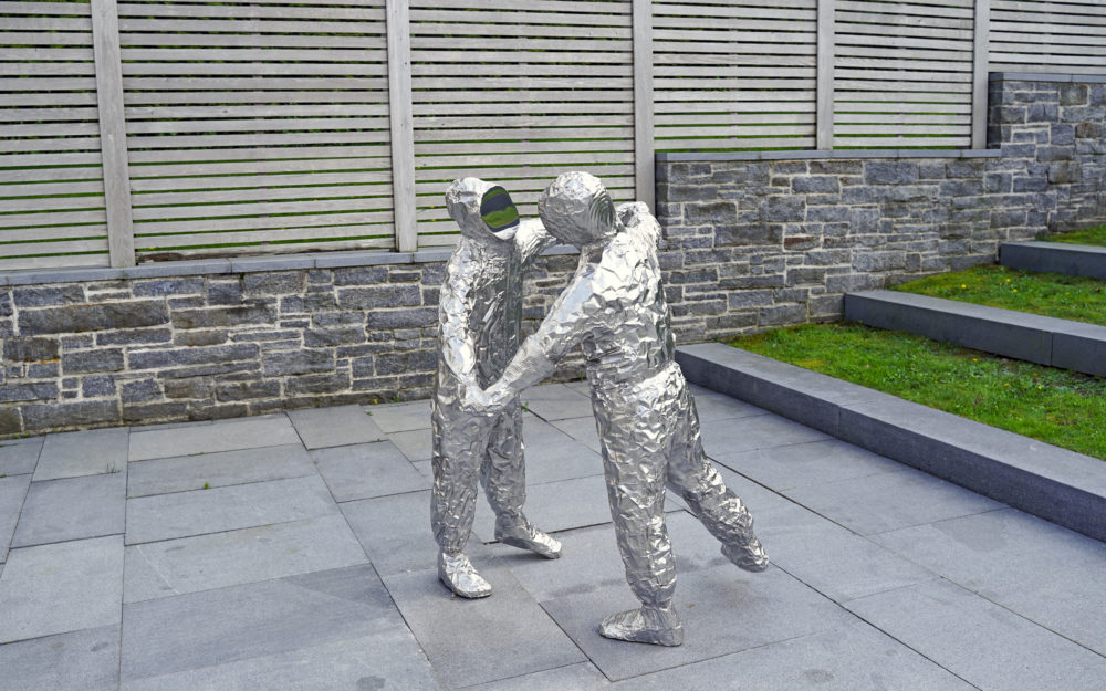 Two figures made out of crumpled baking pans cast in polished stainless steel