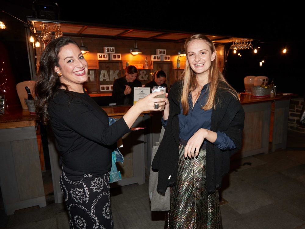 Two women with drinks by a bar truck.