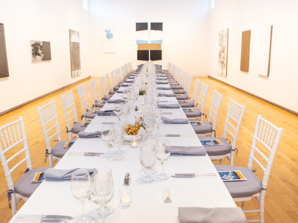 A long set table in a gallery.