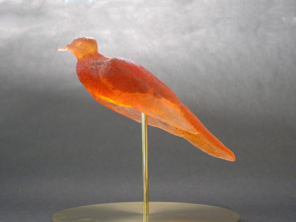 Orange songbird on brass post and stand.
