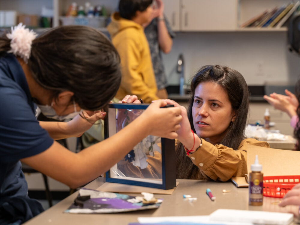 Artist Amanda Martínez assisting a student with a project.