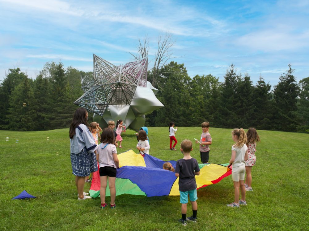 Children and teacher playing outside with a colorful parachute