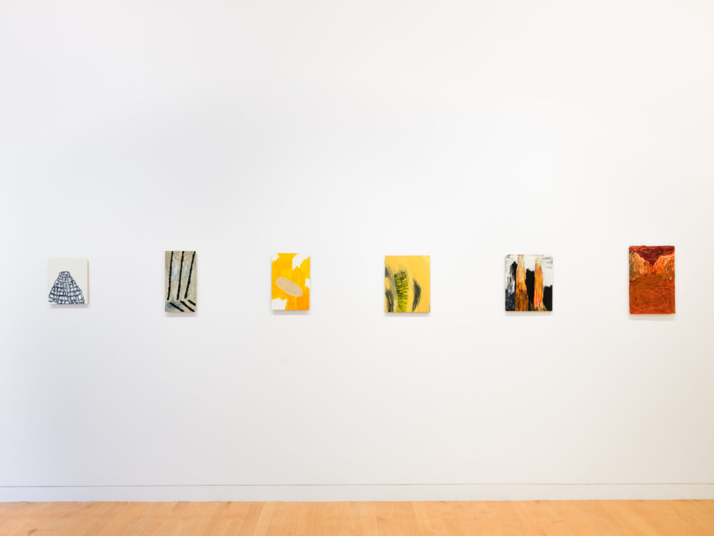 A white wall with a row of small abstract paintings