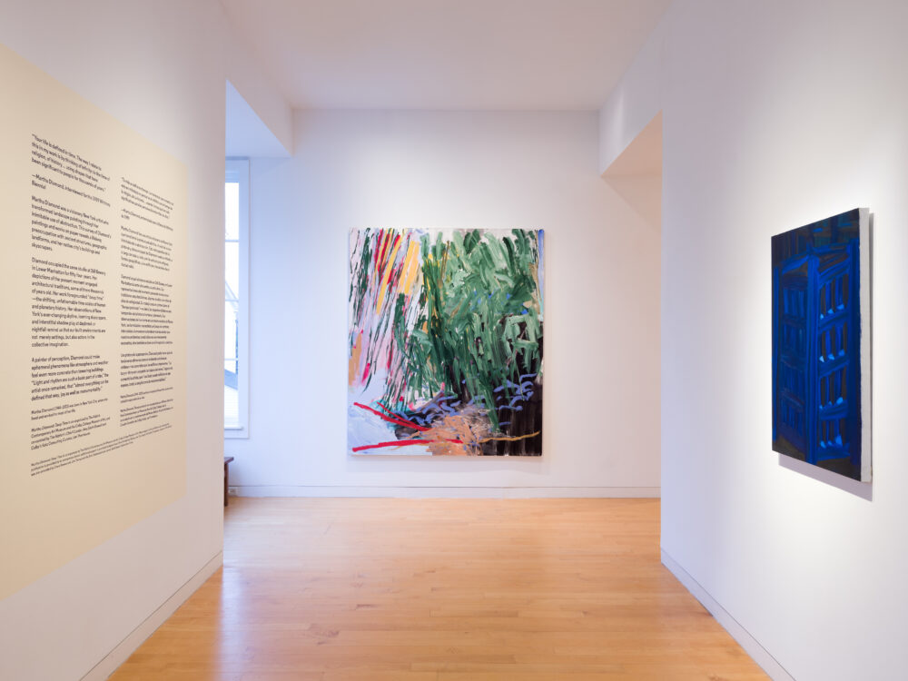 A hallway with an abstract painting at center and a blue painting on the right wall.