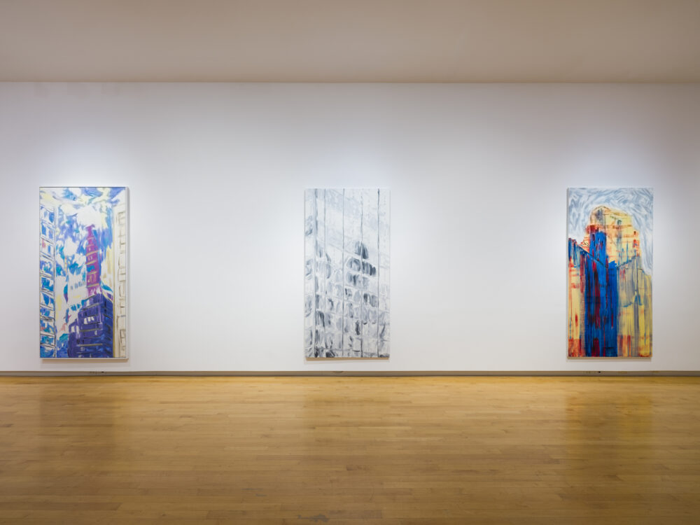 Three large vertical paintings hung on a white wall