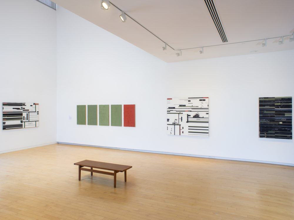 Gallery with four abstract paintings on the wall and a wooden bench in the middle of the room.