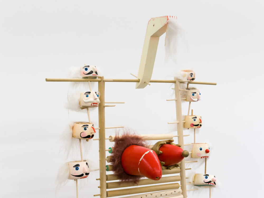 A sculpture with two central red objects and suspended nutcracker heads.